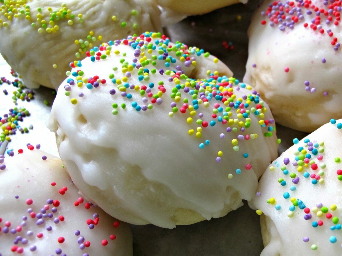 Closeup showing crisp, firmed white citrus icing and pastel sprinkles covering the top of the cookie.