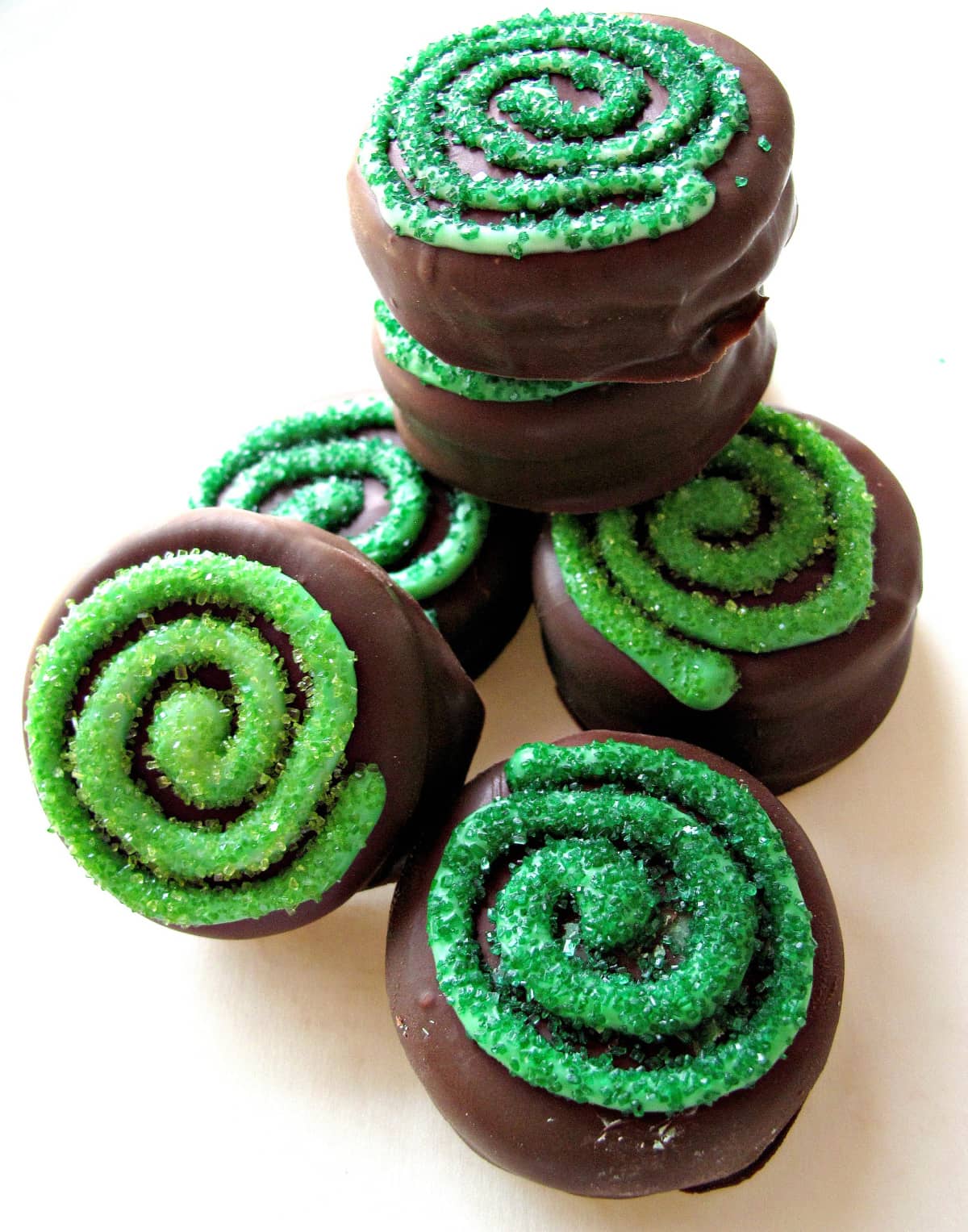 Chocolate Covered Oreos with a green sparkle sugar coated swirl on top.