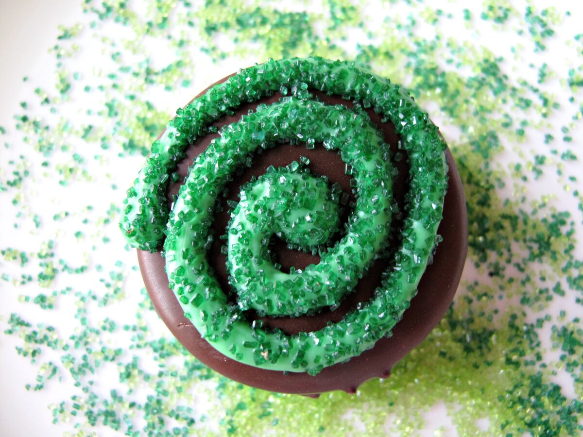 Closeup showing green colored sugar on top of piped green candy coating swirl.