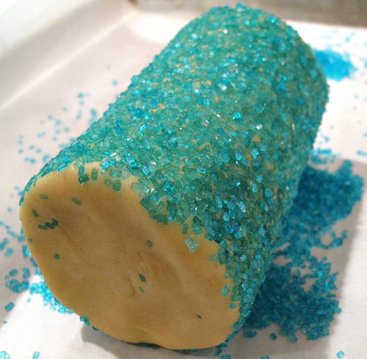 Log of sugar cookie dough coated in blue decorating sugar.