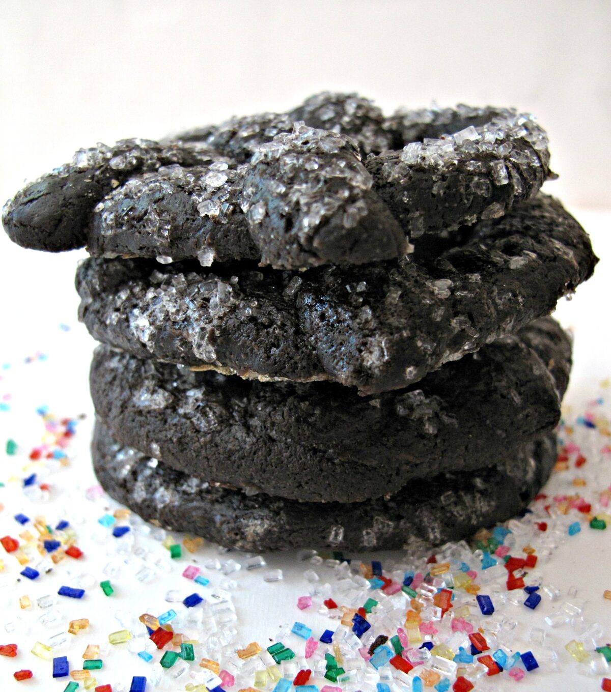 A stack of pretzel shaped chocolate cookies sprinkled with large crystal sugar.