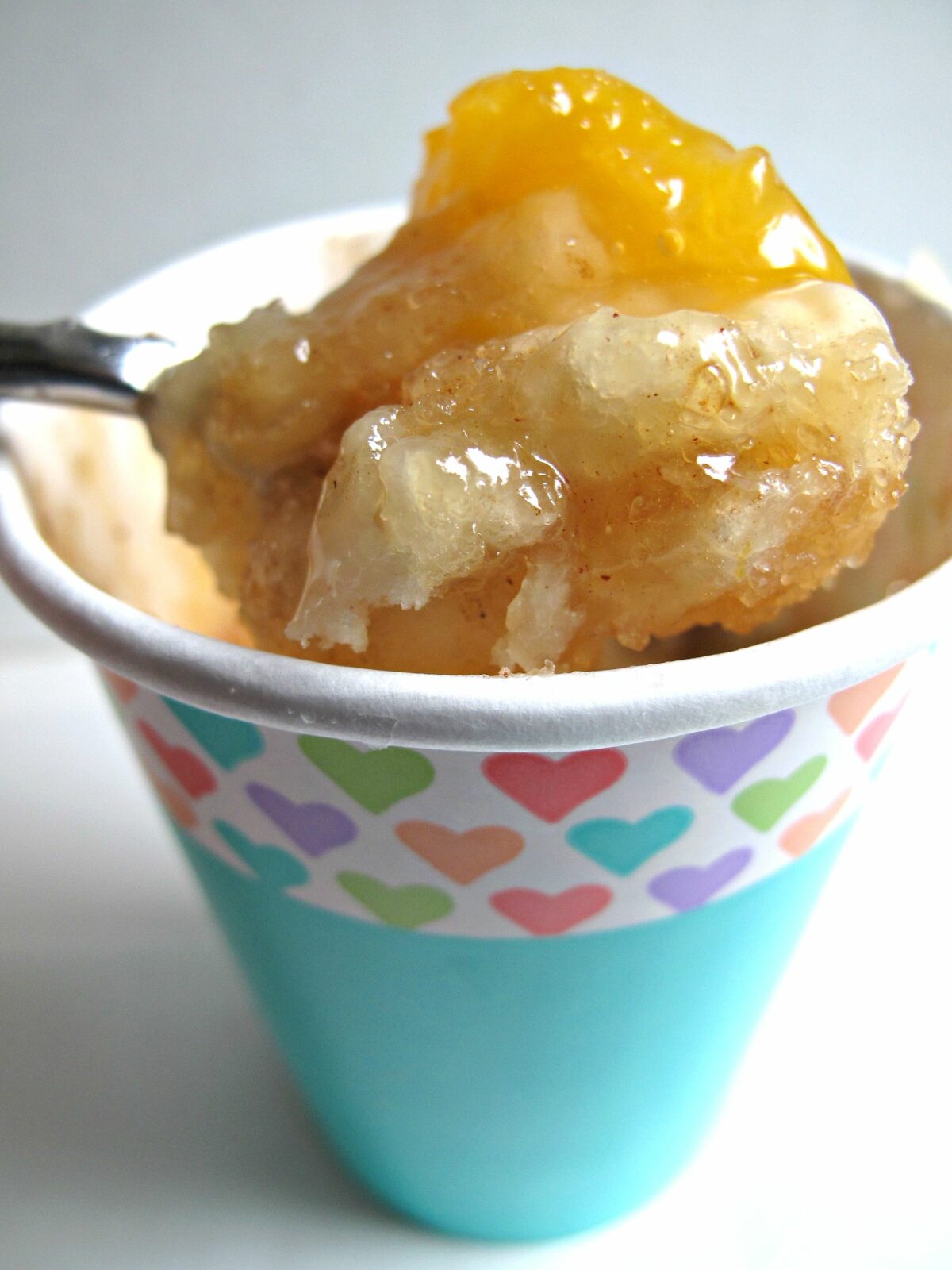 A spoonful of Peach Cobbler cooked in a microwave safe paper cup.