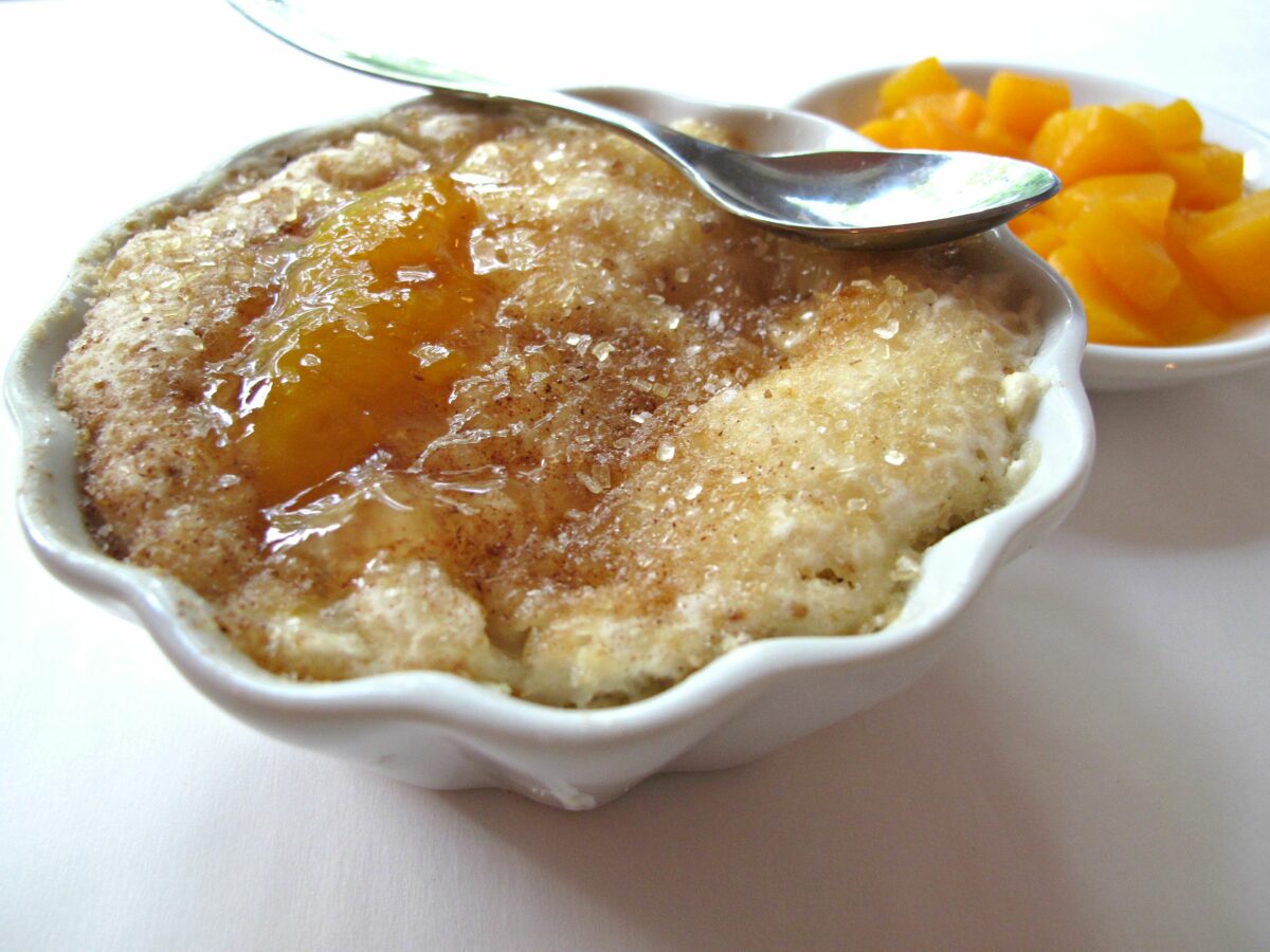 Closeup of sugar encrusted cobbler crust with peach juice on top.