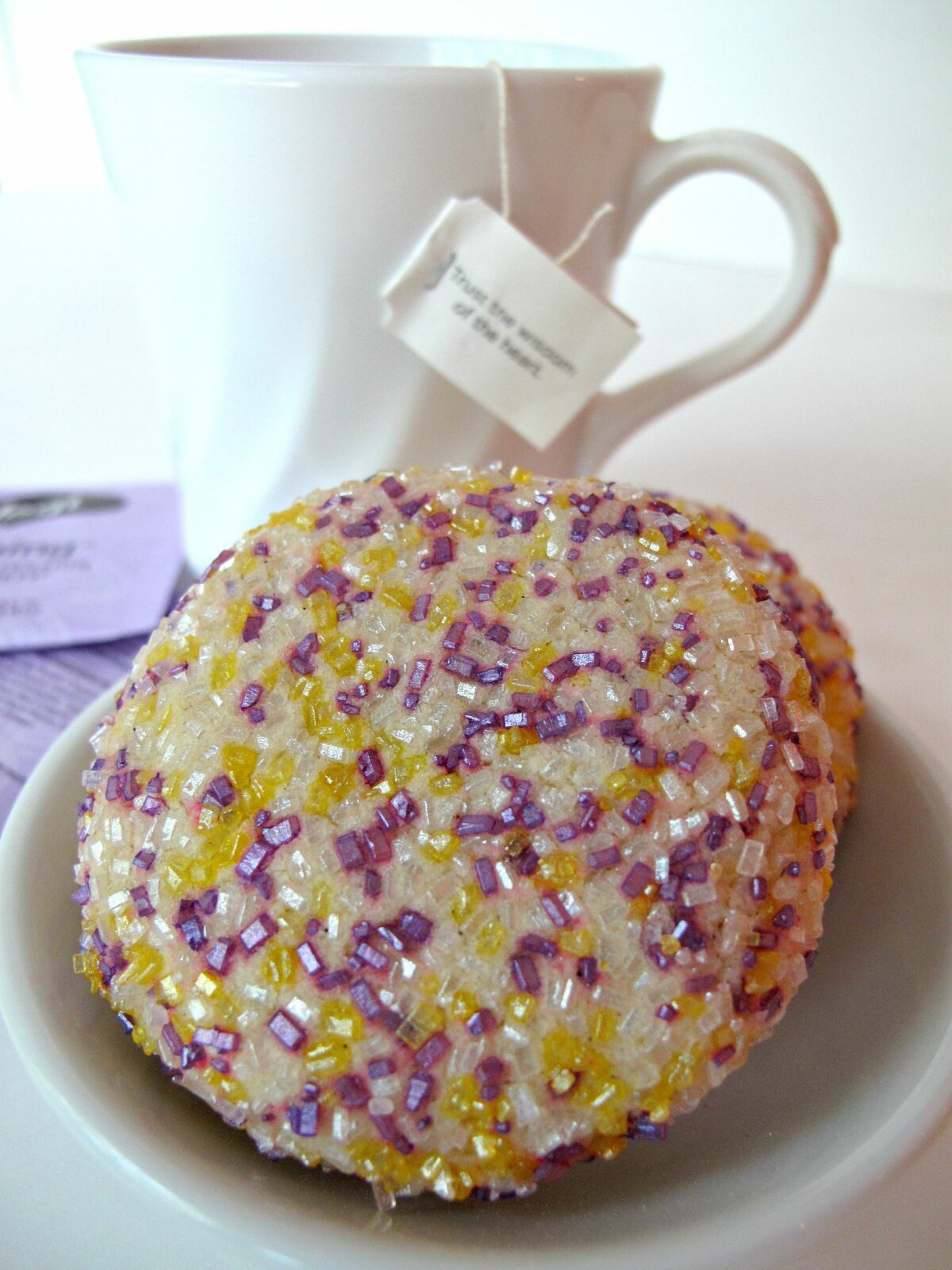 Closeup of a sugar coated cookie in front of a mug of tea.