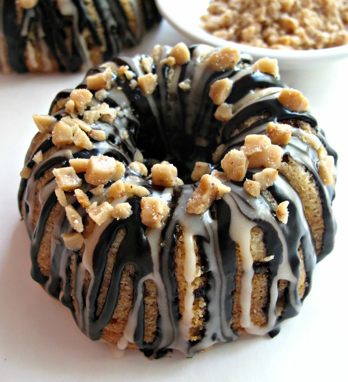 Vanilla Bean Mini-Bundt Cakes with Chocolate-Toffee Crunch close-up showing drizzle and toffee bits.