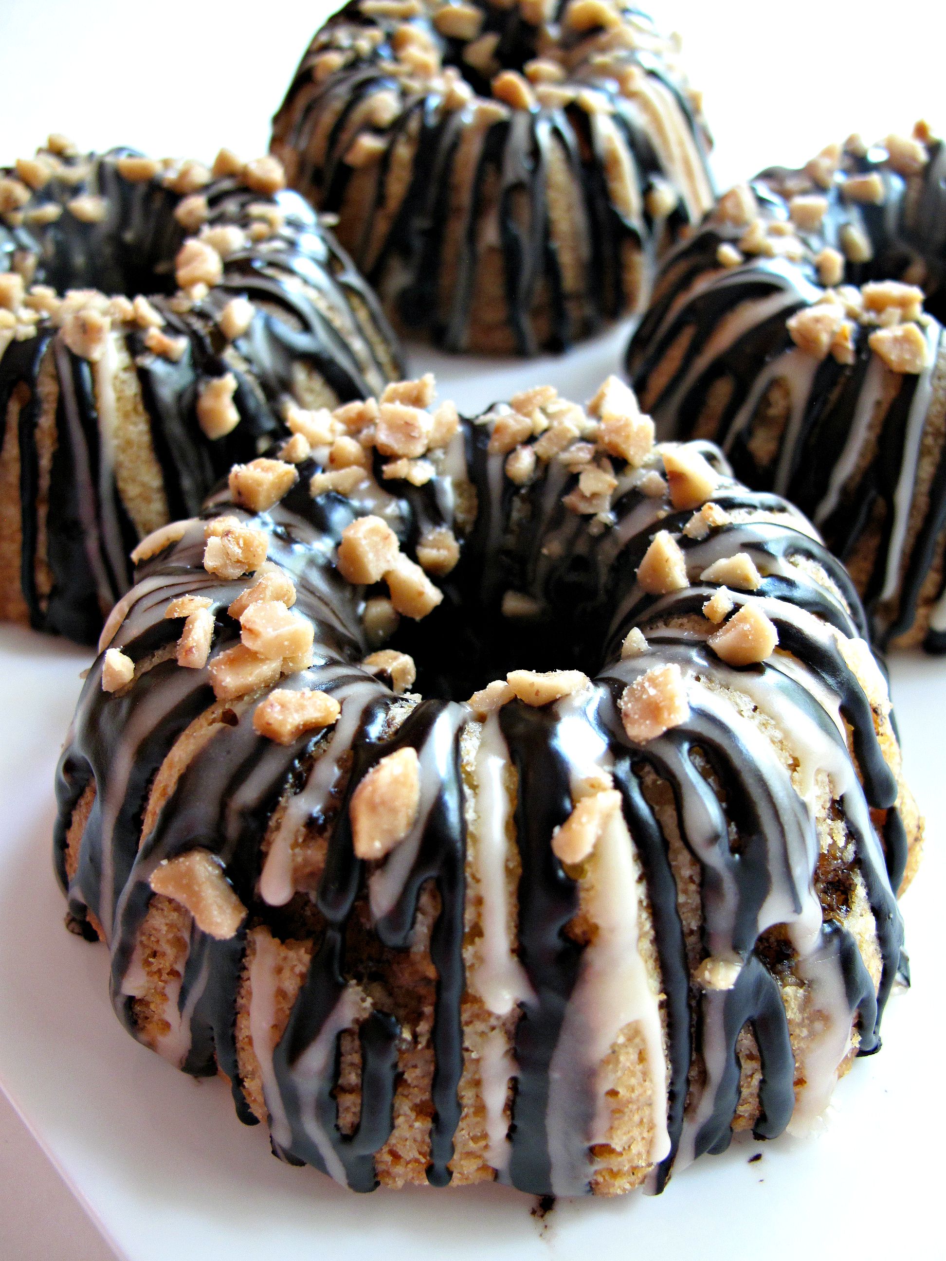 Closeup of Vanilla Bean Mini-Bundt Cake topped with chocolate and vanilla drizzle and toffee bits.