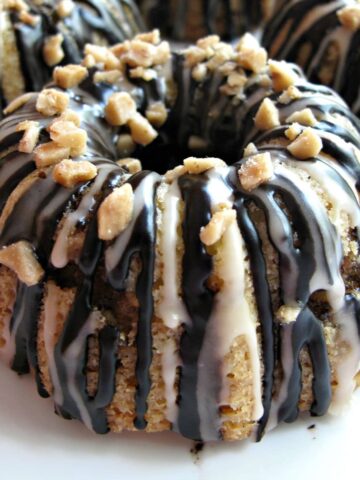 Close up of mini bunt cake with chocolate and vanilla drizzle and toffee bits on top.