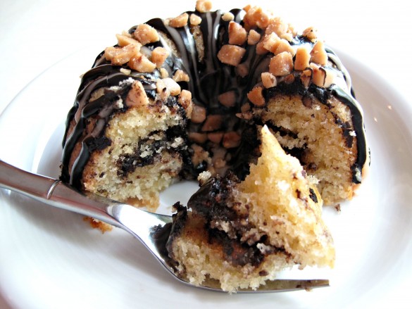 A fork full of Vanilla Bean Mini-Bundt Cakes with Chocolate-Toffee Crunch in front of the cake showing interior