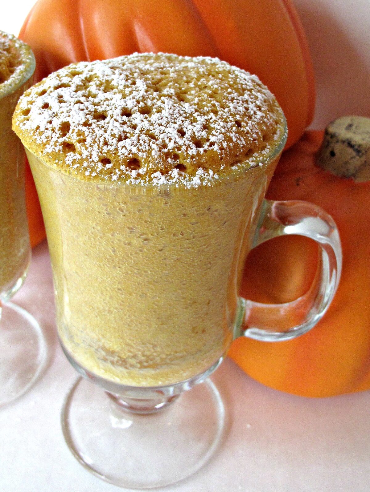 Pumpkin Spice mug cake in a glass mug topped with powdered sugar.