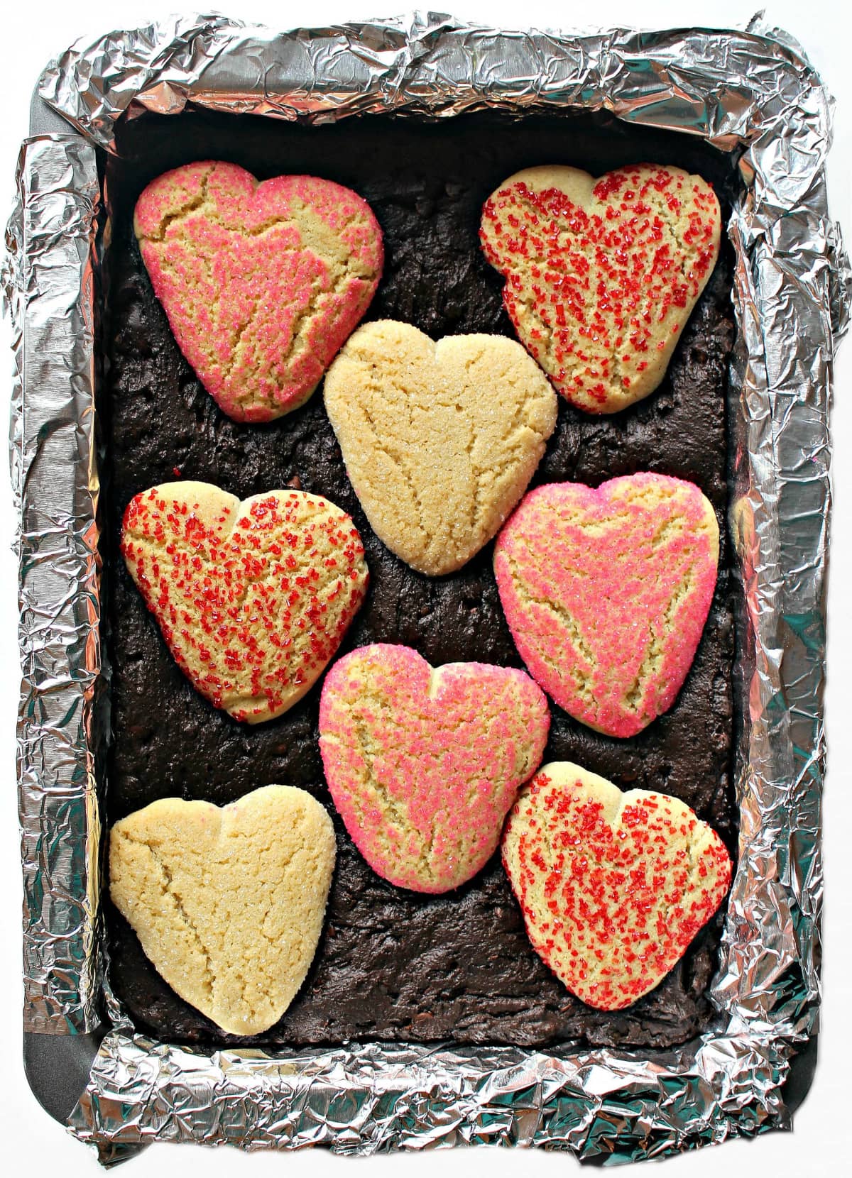 Valentine Brownies with heart shaped cookies on top in a pan.