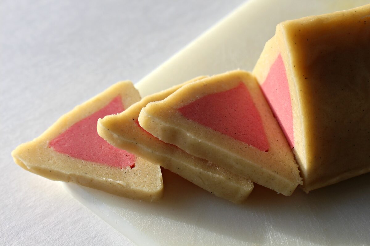 Closeup of triangle dough log with pink triangle center being sliced.