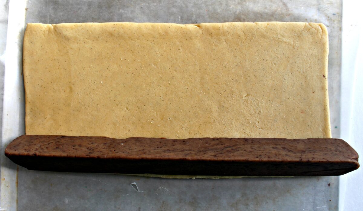 Triangle log of chocolate dough on top of flat rectangle of vanilla dough.