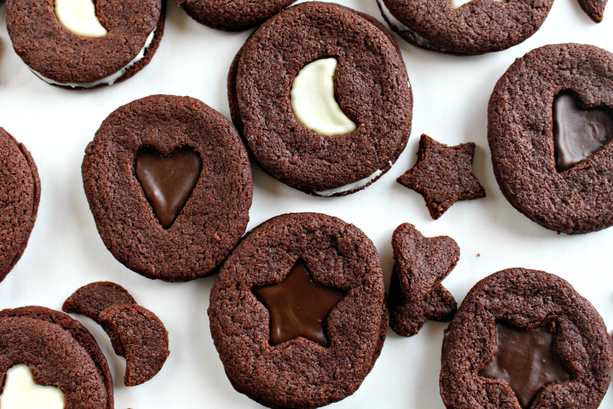 Closeup of chocolate sandwich cookies with cutouts on top.