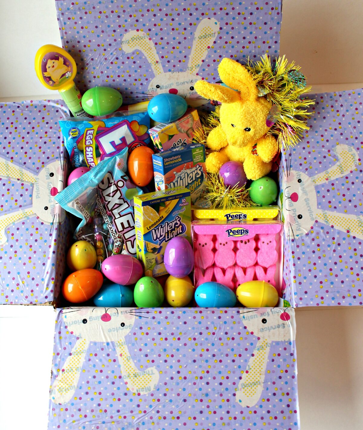  Eater care package with decorated box flaps filled with Easter candy and toys.