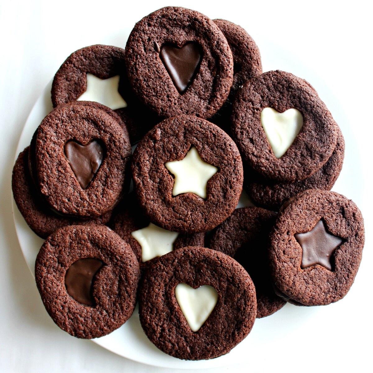 Sandwich Cookies with decorative heart, moon, and star cutouts on a white plate.