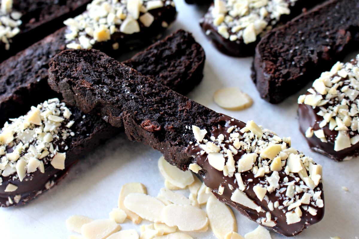 Closeup showing dark chocolate cookie with chocolate dipped end coated in almond bits.