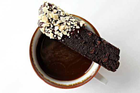 Double Chocolate Passover Biscotti (GF) balanced on rim of mug of coffee