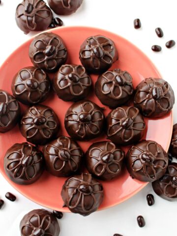 Chocolate coated brownie-bites on a plate.