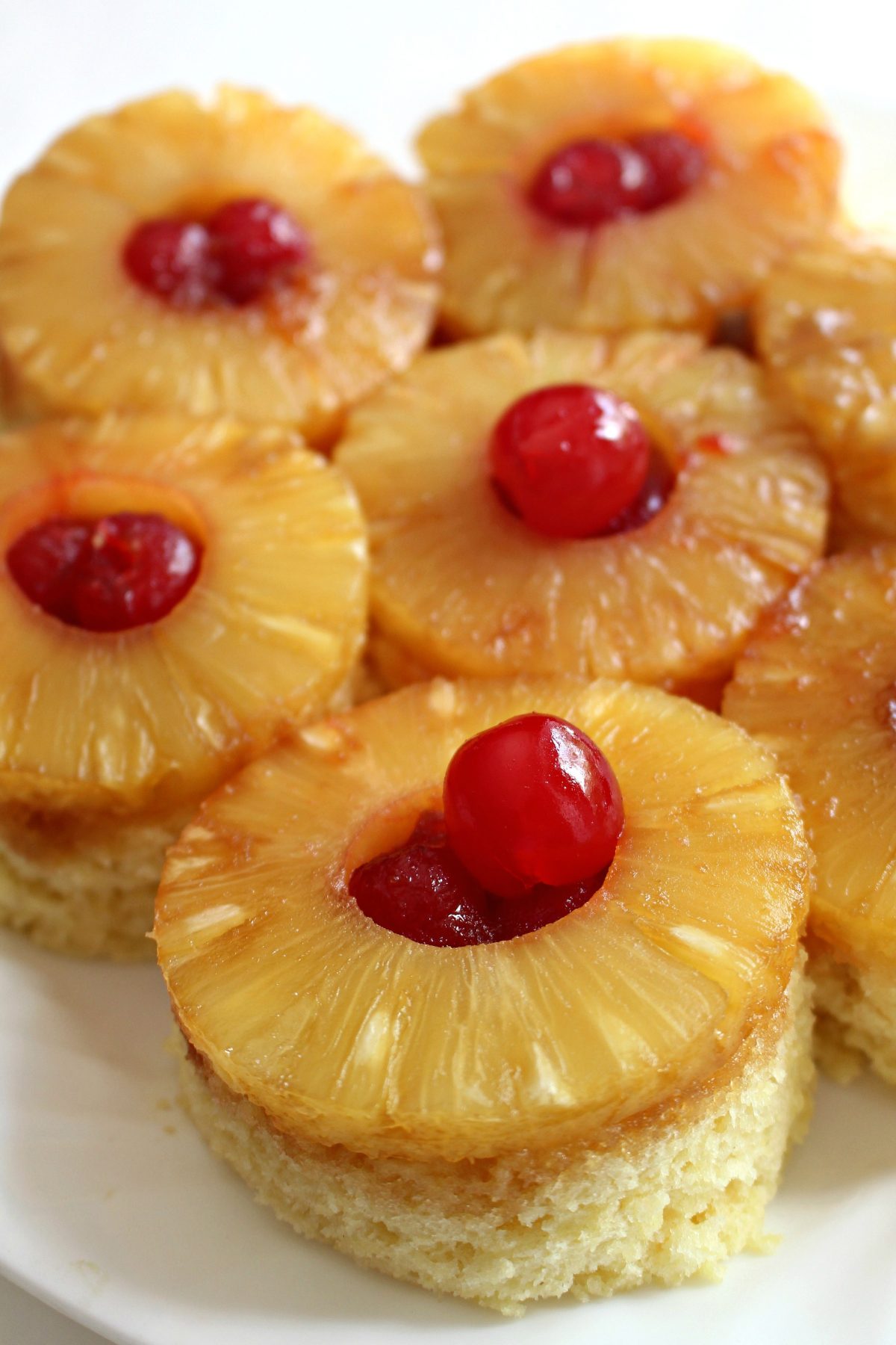 Pineapple Upside Down Mug Cake on a plate topped with a pineapple ring and a cherry.