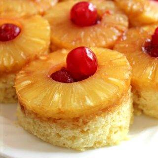 Closeup of pineapple slice and maraschino cherry on top of vanilla mug cake.