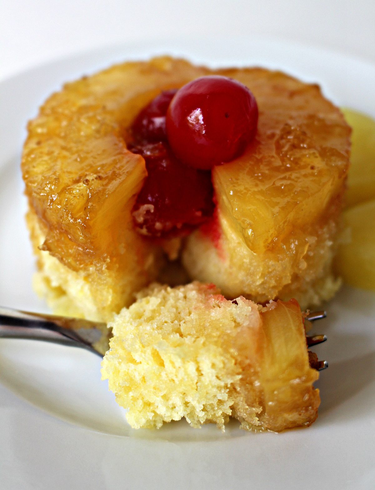 Pineapple Upside Down Mug Cake on a plate with a forkful of cake.