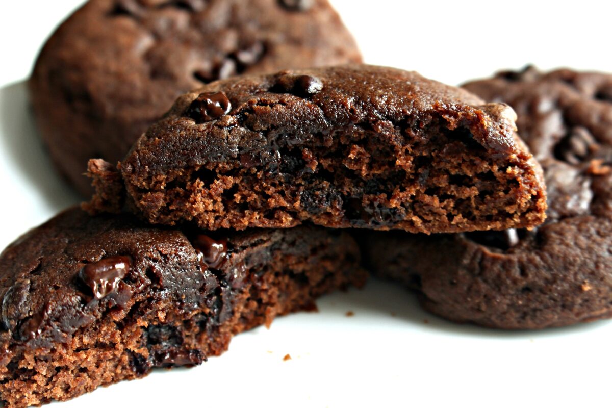 A chocolate cookie with nibs, cut in half to show thick, chewy interior.