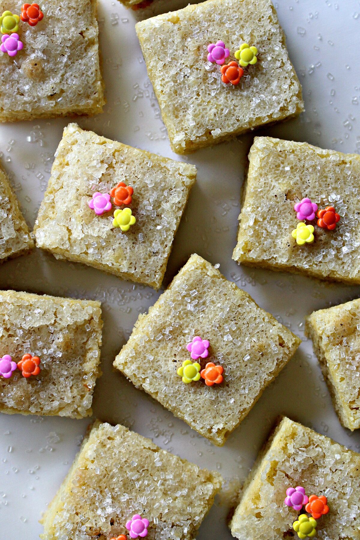 Square sugar cookie bars topped with sparkling sugar and flower sprinkles.