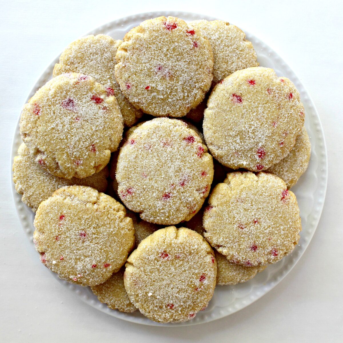 Disc shaped lemon cookies with bits of peppermint showing in the dough, topped with sugar.