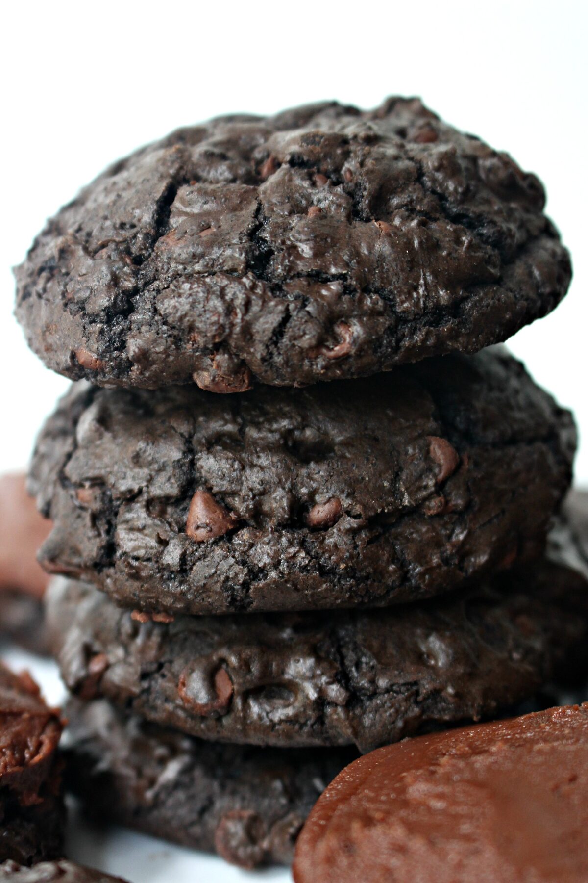 A stack of thick, dark chocolate, brownie cookies speckled with chocolate chips.