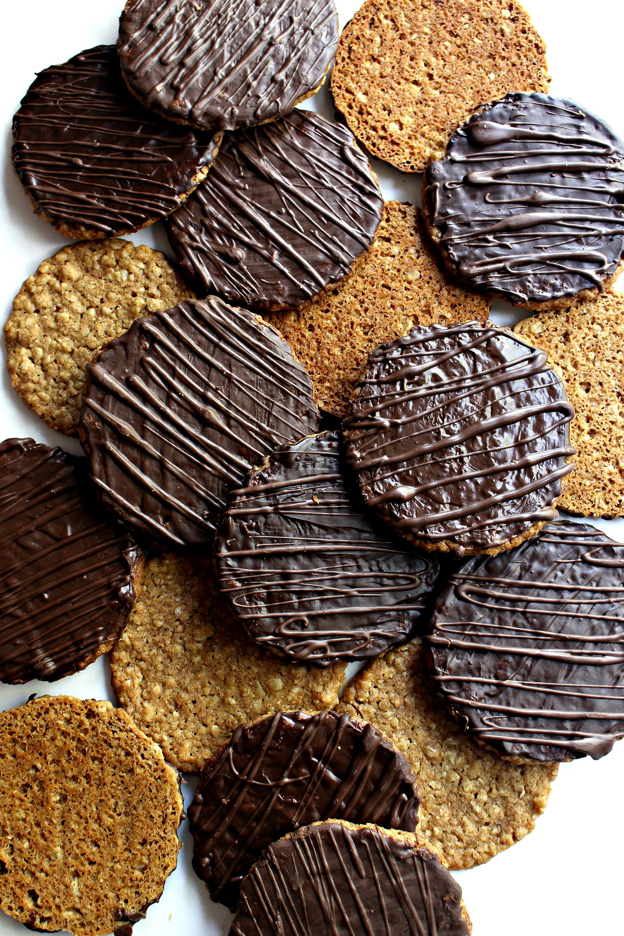 Hobnobs Oat Cookies scattered on a white surface, oat side or chocolate coated side facing up. 