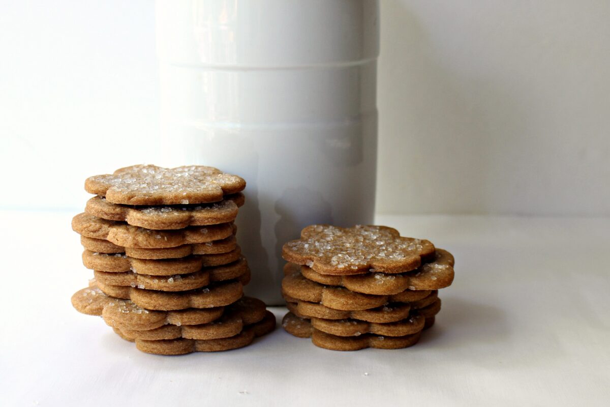Two stacks of thin cookies in from of a cookie jar.