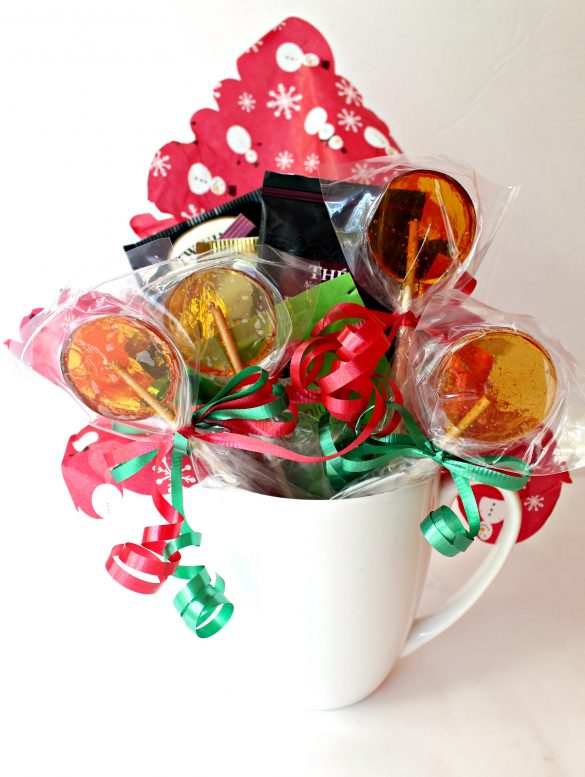 Honey Lollipops tied with red and green ribbons in a white mug with tea bags for gift giving.