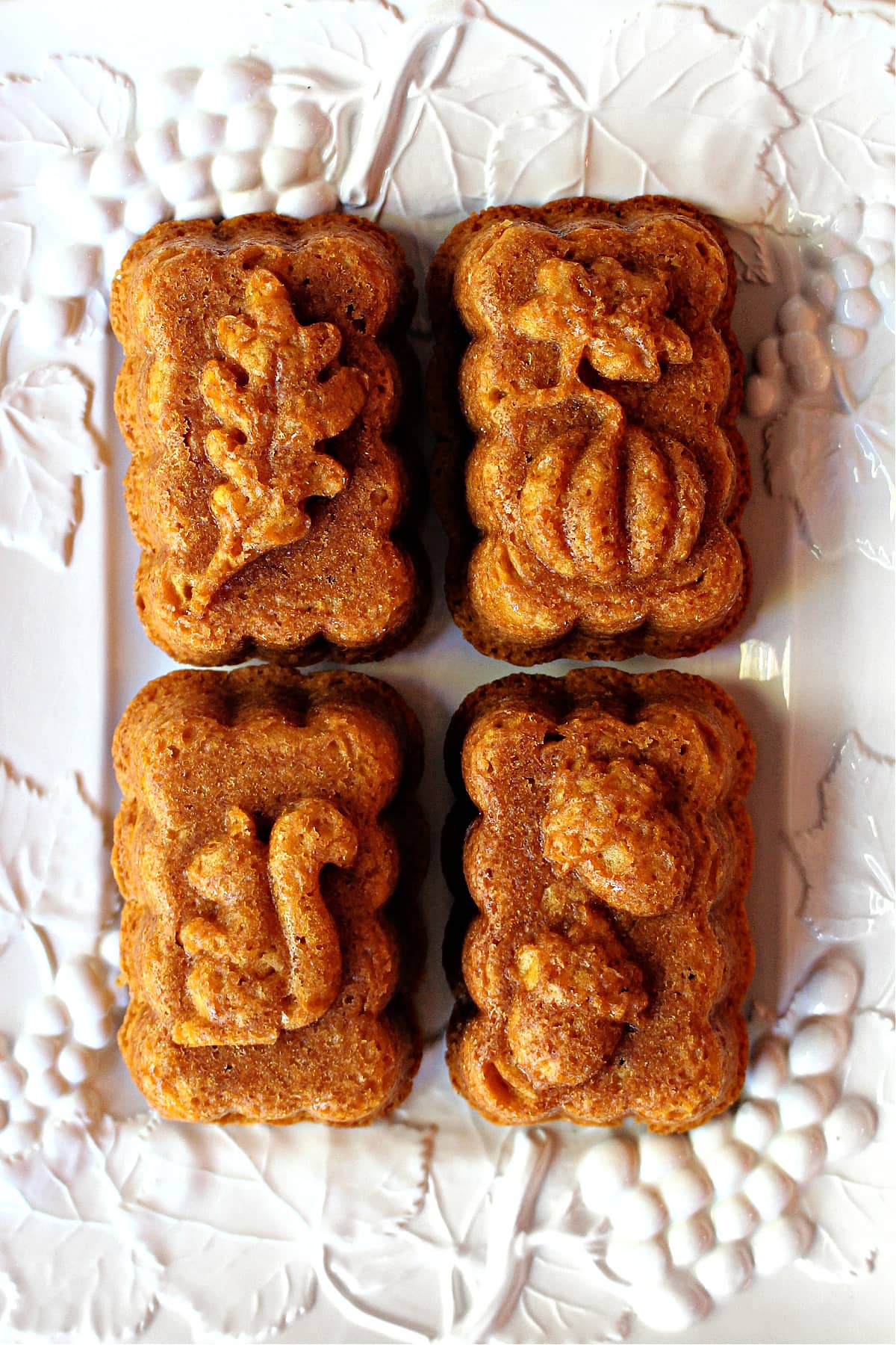 Four mini Pumpkin Butterscotch Loaf Cakes on a white platter.