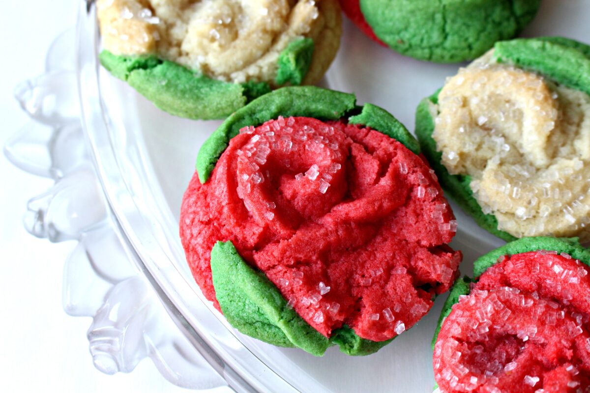 Closeup of a red rose sugar cookie with green cookie dough leaves.