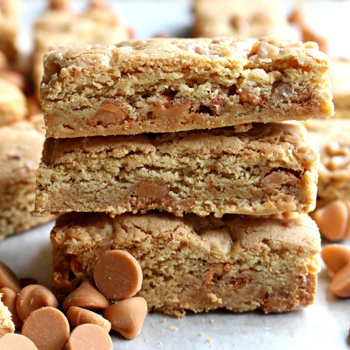 Stack of three butterscotch blondies showing the thick edges and chips inside.
