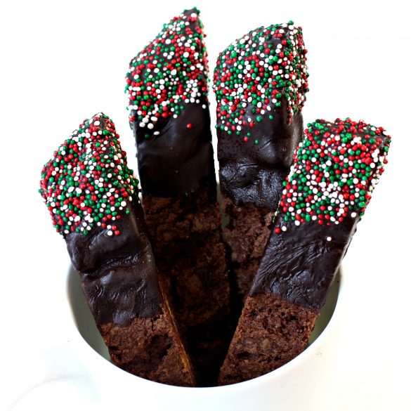 Close up of chocolate dipped ends of biscotti with red, white, and green nonpareil sprinkles.