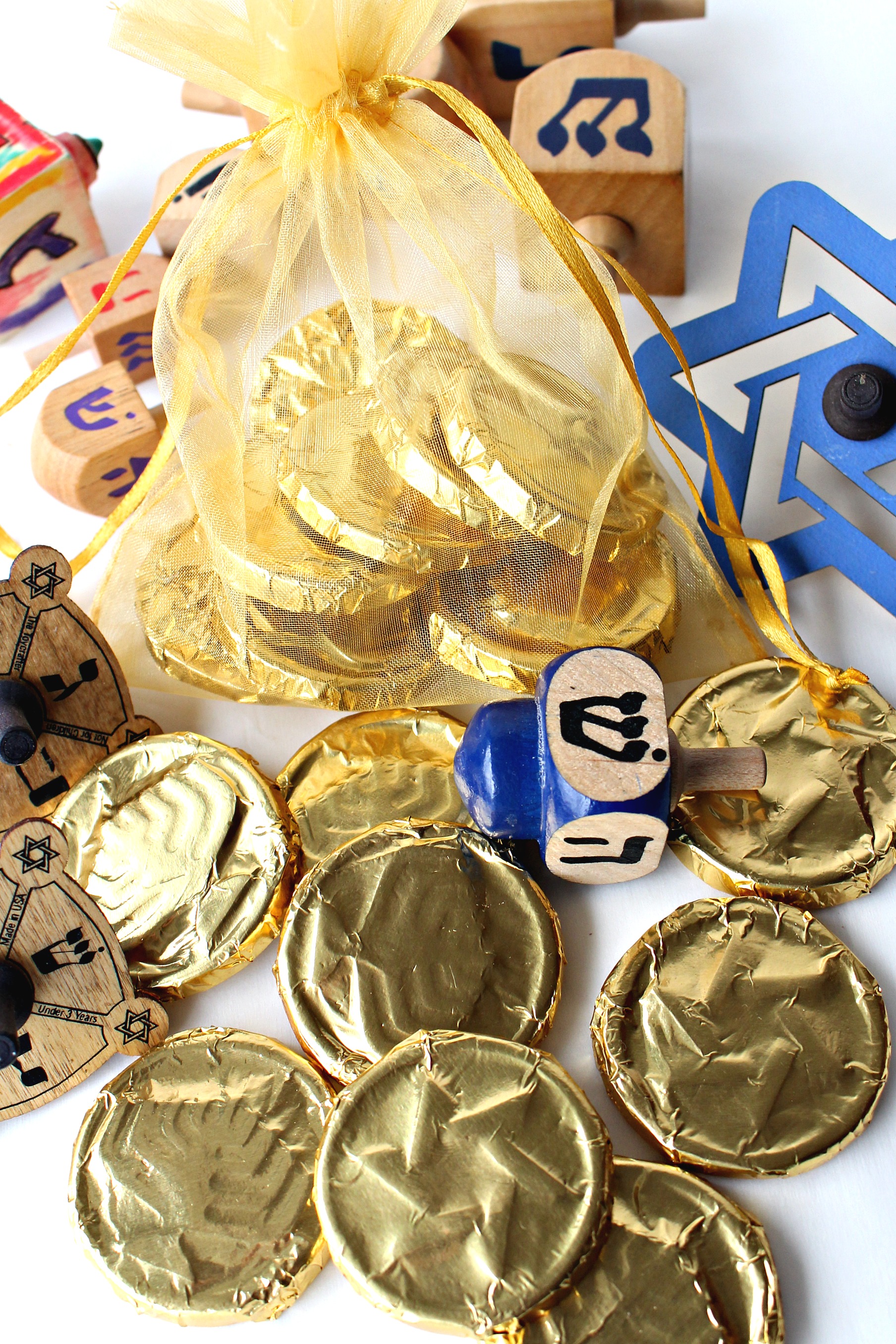 Gold foil wrapped Homemade Chocolate Coins (Hanukkah Gelt) with small, wooden dreidels