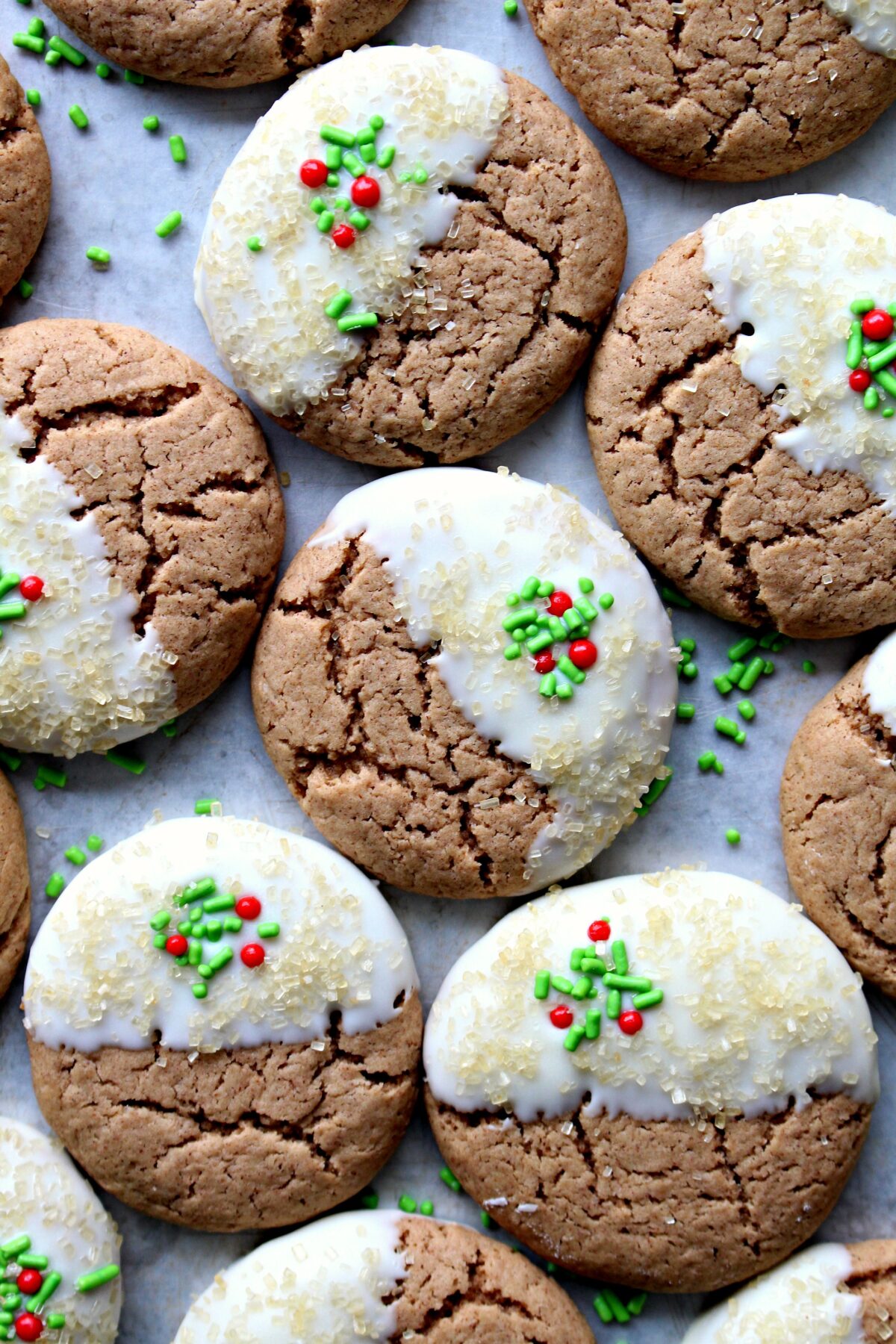 Gingerbread Spice Cookies with crackled tops half dipped in white chocolate with red and green sprinkles.