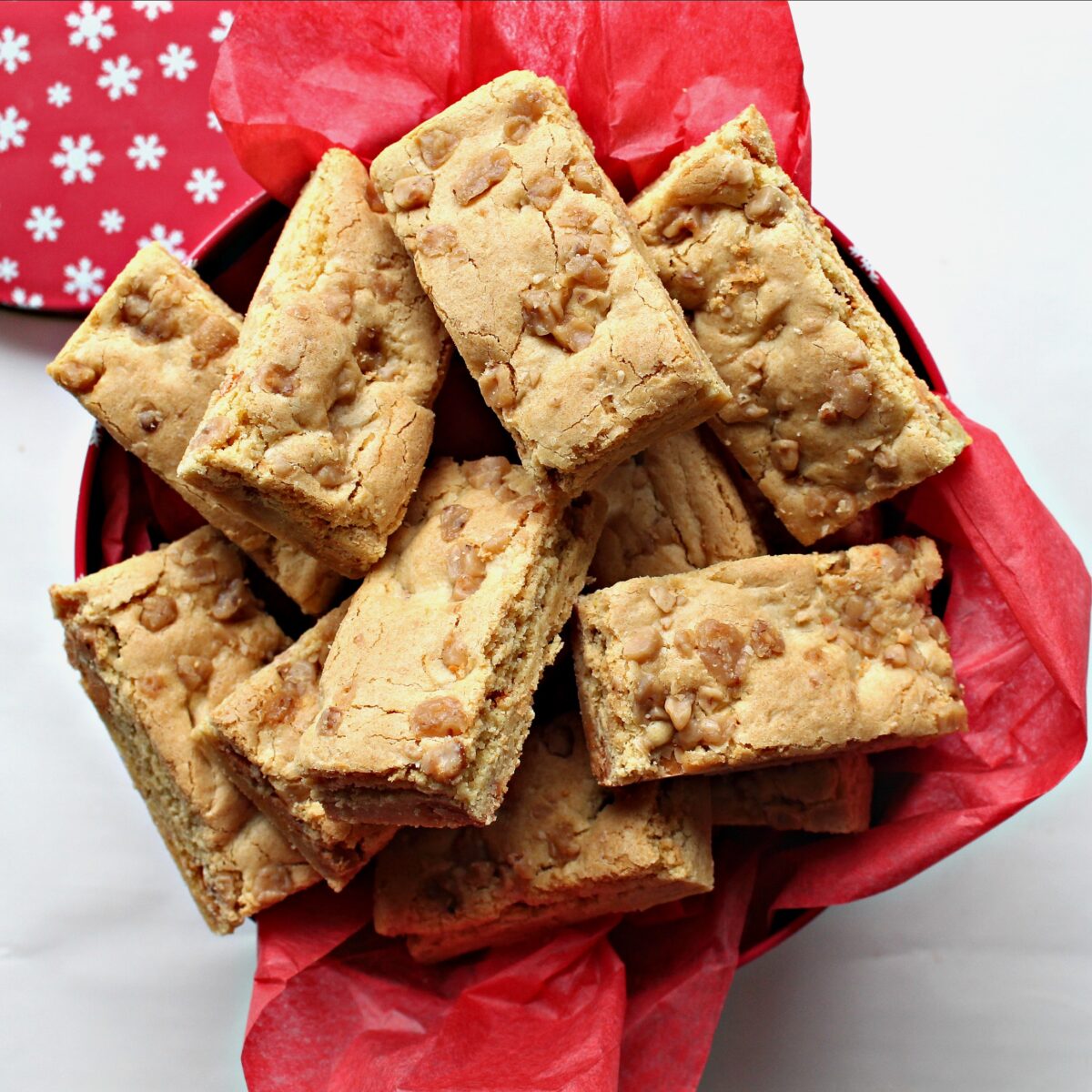 Butterscotch bars in a gift tin lined with red tissue paper.