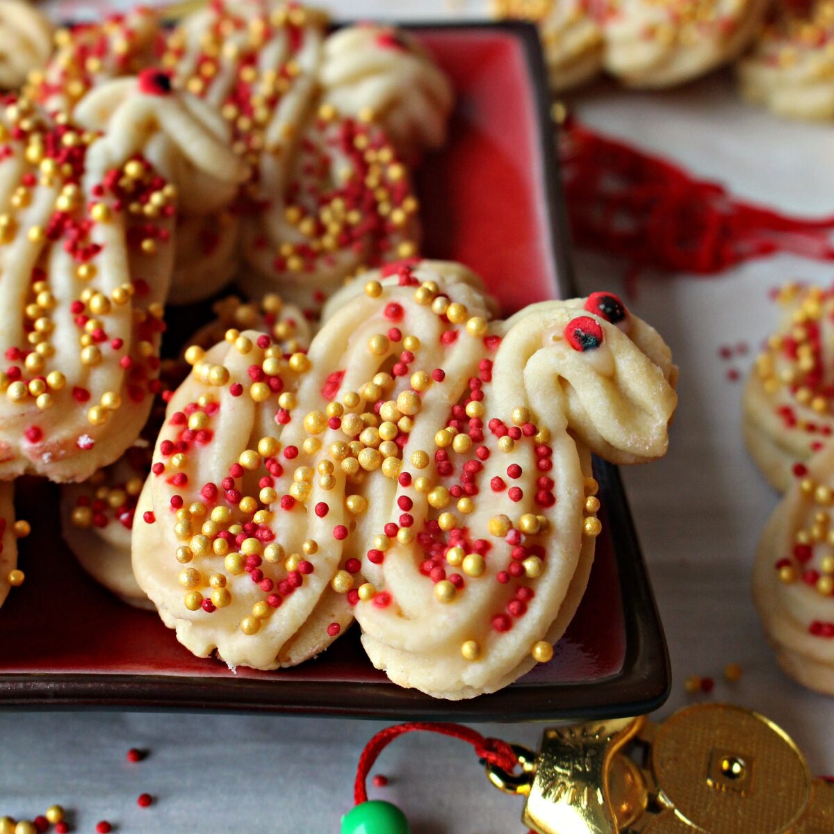 Closeup of swirled Cookie Dragons ( 龙饼 ) with red sprinkle eyes and red and gold nonpareil sprinkled body.