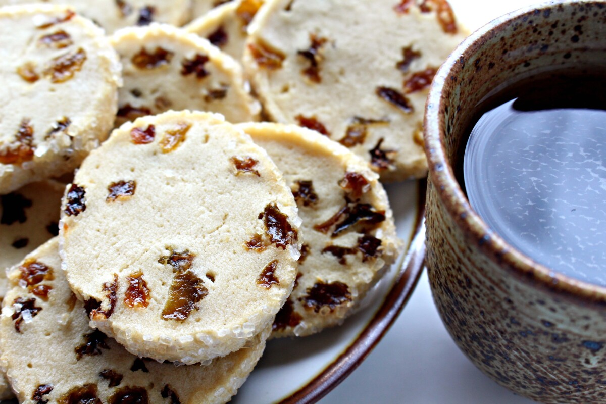 Closeup of a raisin cookie next to a cup of coffee.