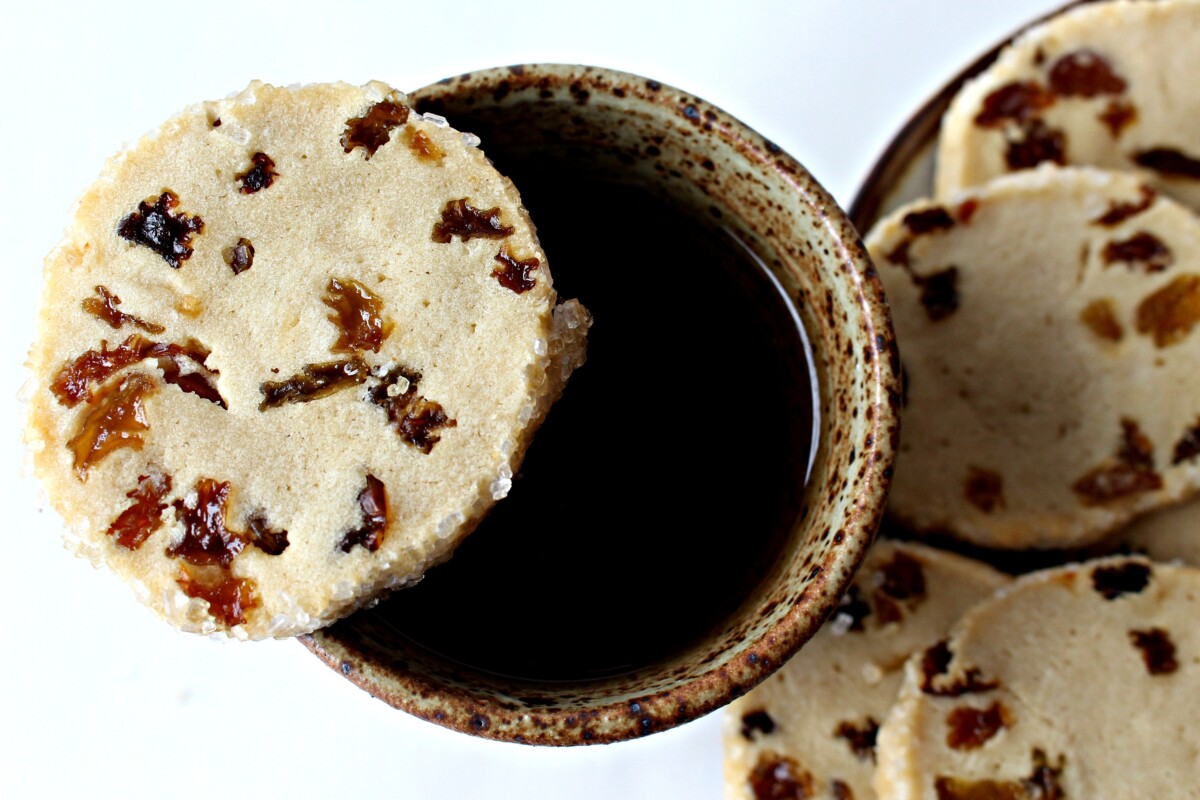 A raisin cookie on the edge of a coffee mug.