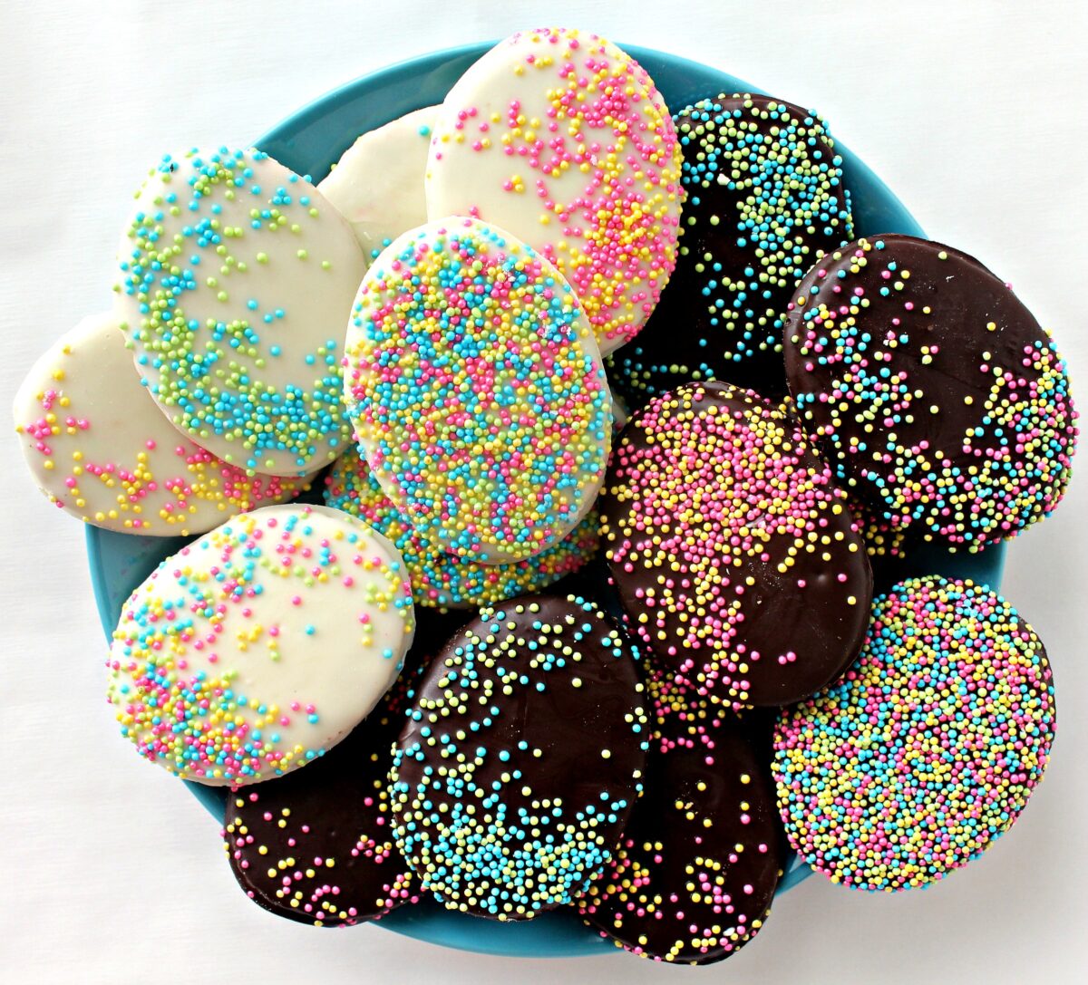  Easter Egg cookies covered in chocolate and sprinkles on an aqua plate.