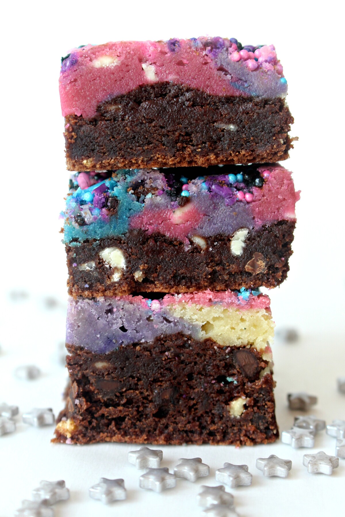 Stack of brownies showing layers of brownie bottoms and colorful blondie tops.