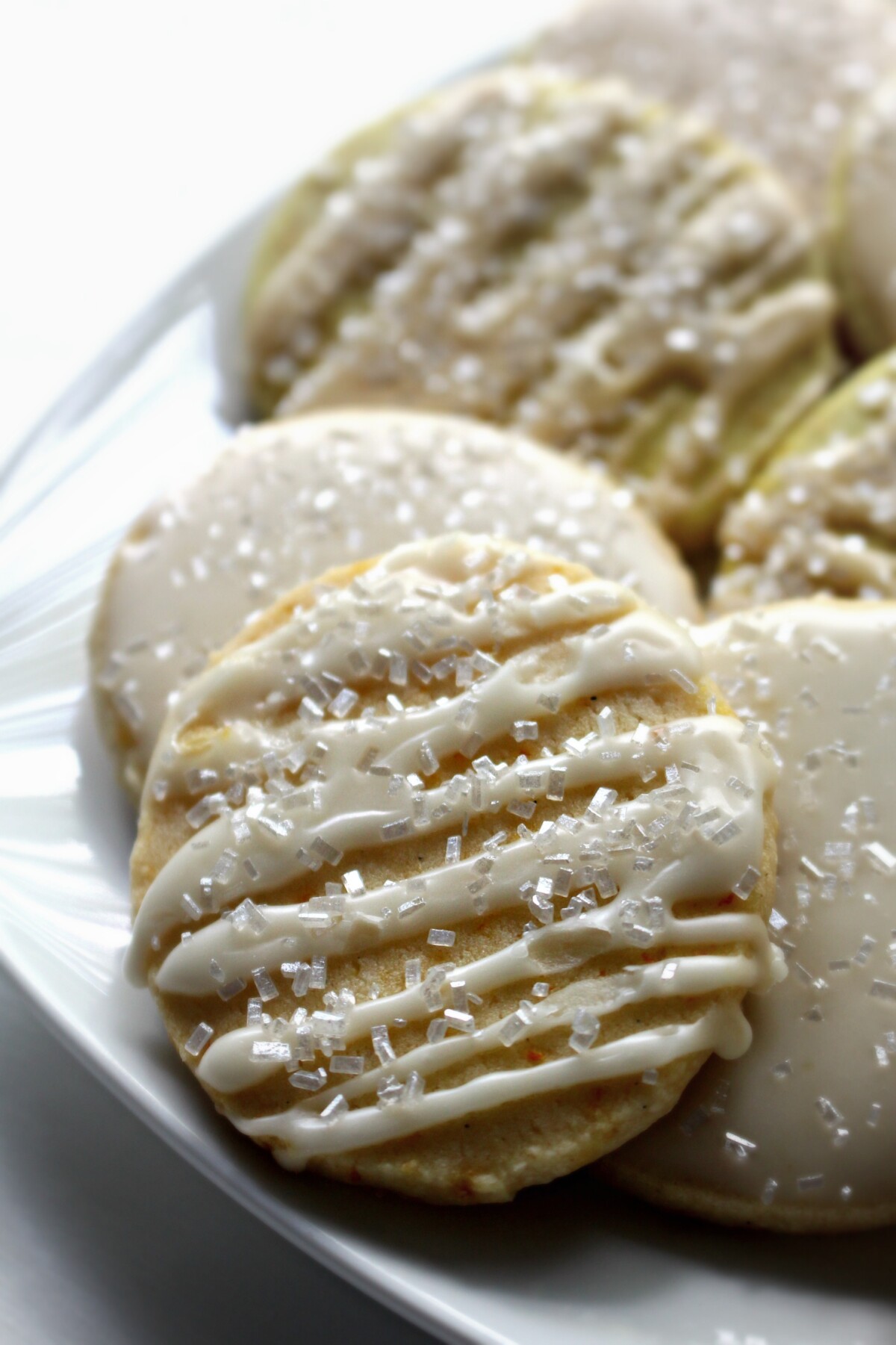 Closeup of iced cookie with sparkle sugar on a white serving plate.