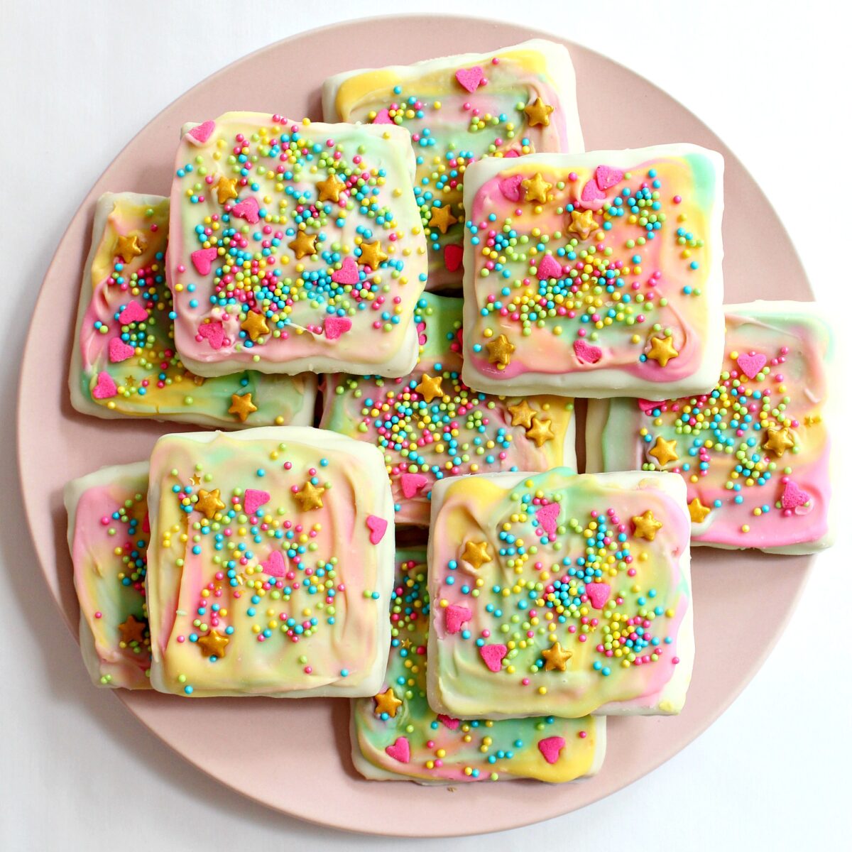 White Chocolate Covered Graham Crackers with sprinkles on a round, pink plate.