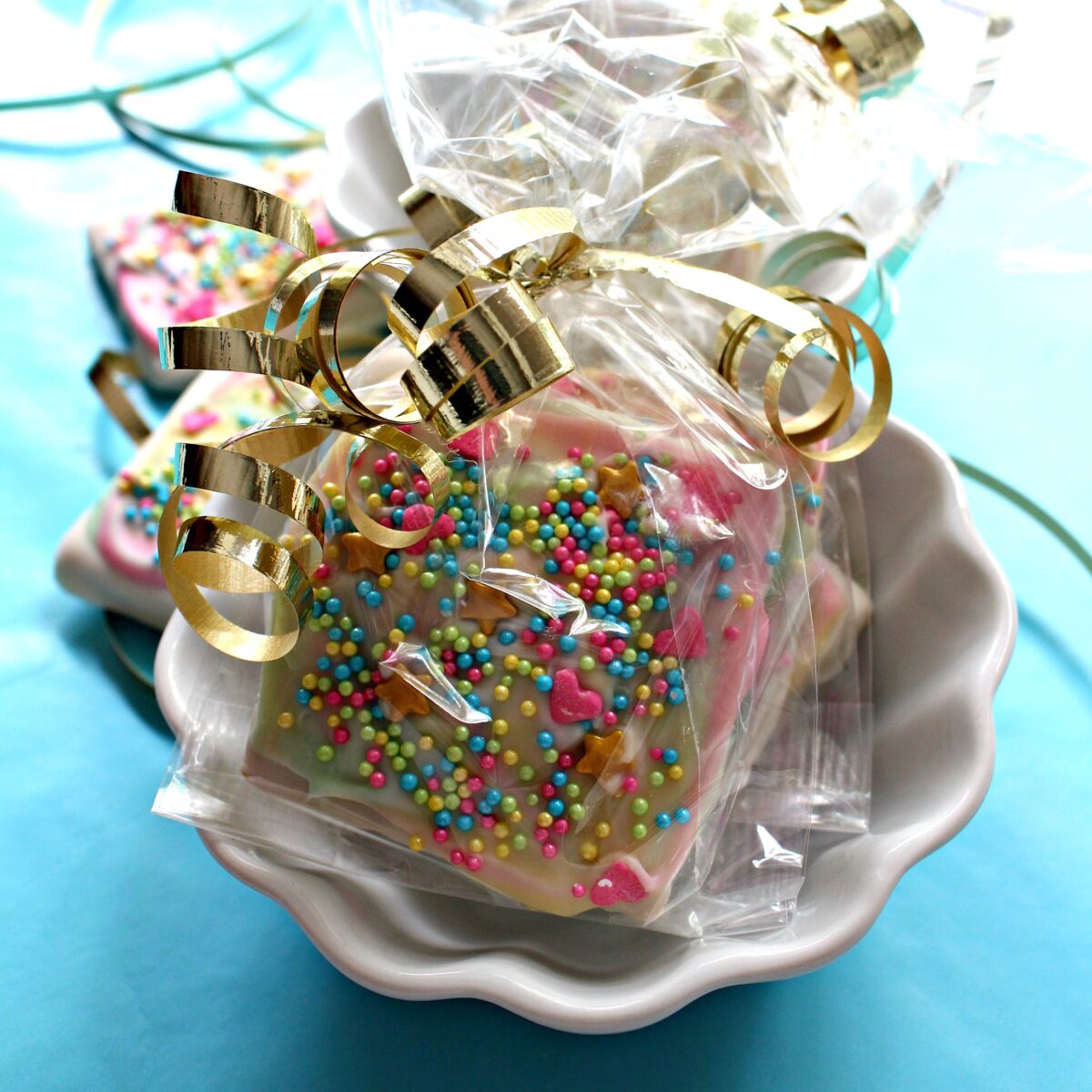 Decorated cookies wrapped in clear cellophane gift bags tied with metalic gold curling ribbon.