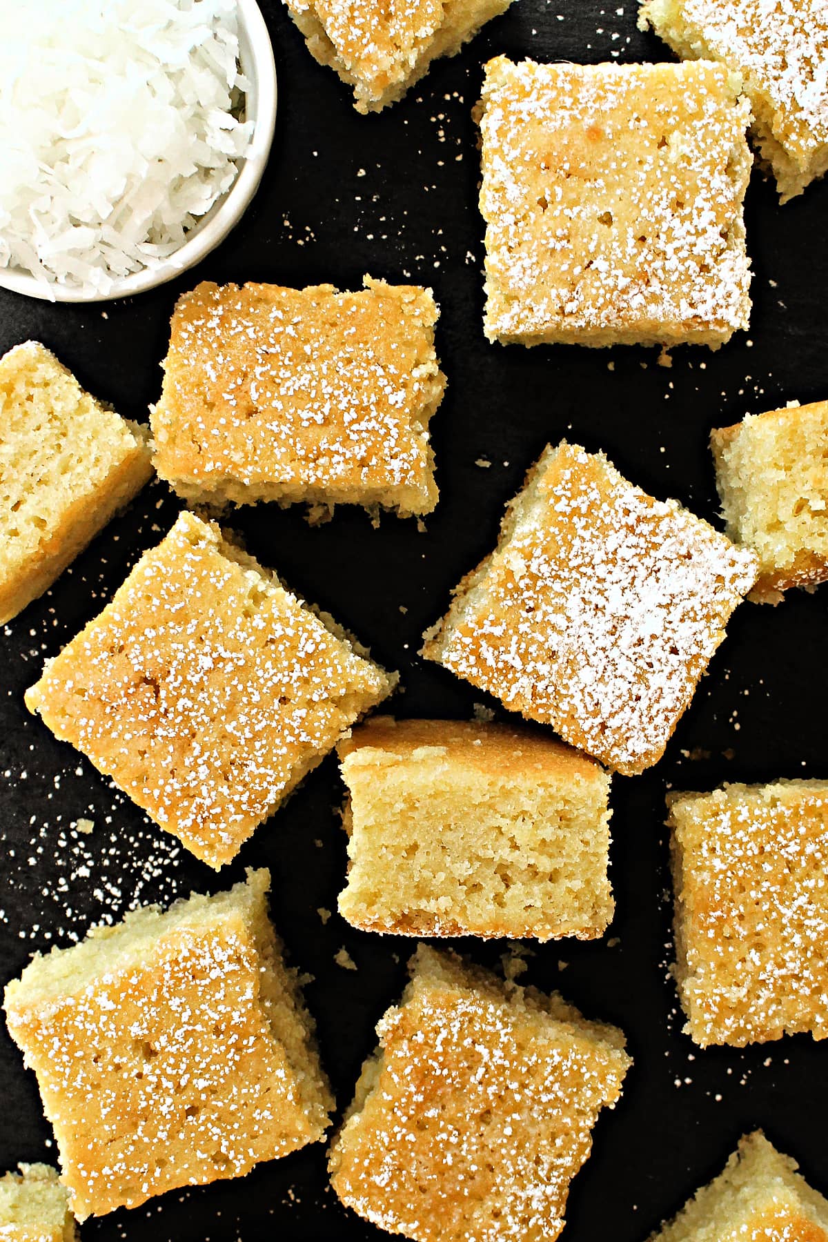 Coconut Milk Snack Cake cut into squares and topped with powdered sugar.
