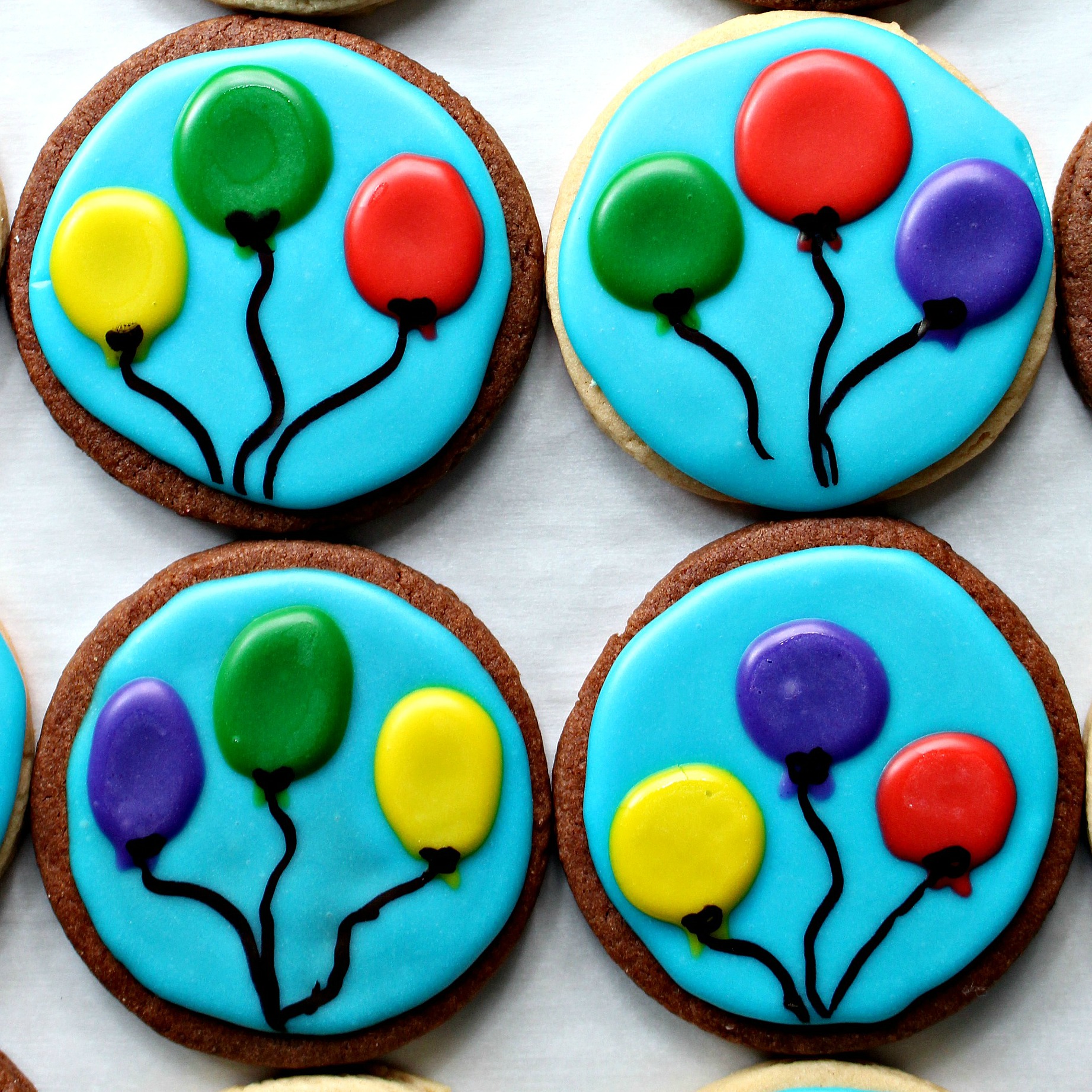 Chocolate and vanilla sugar cookies decorated with blue background and three balloons.