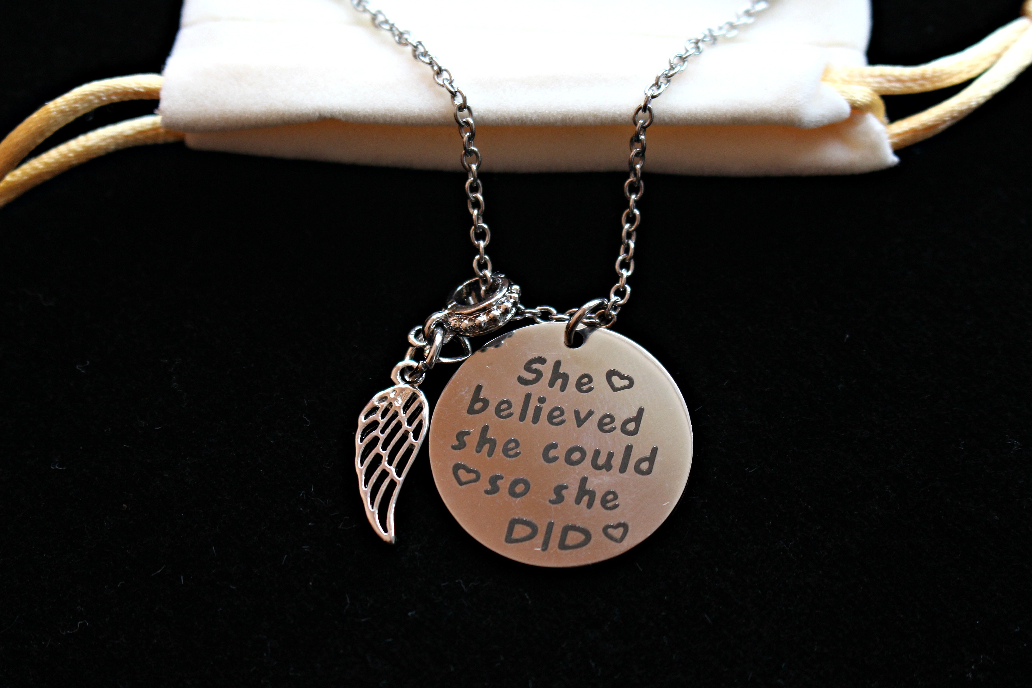 Necklace with silver colored disc charm with motivational quote.